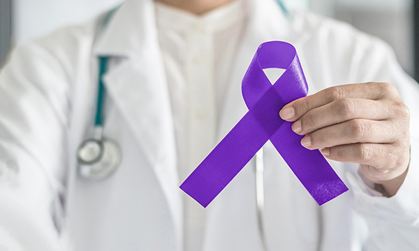 A clinician holds a purple cancer awareness ribbon