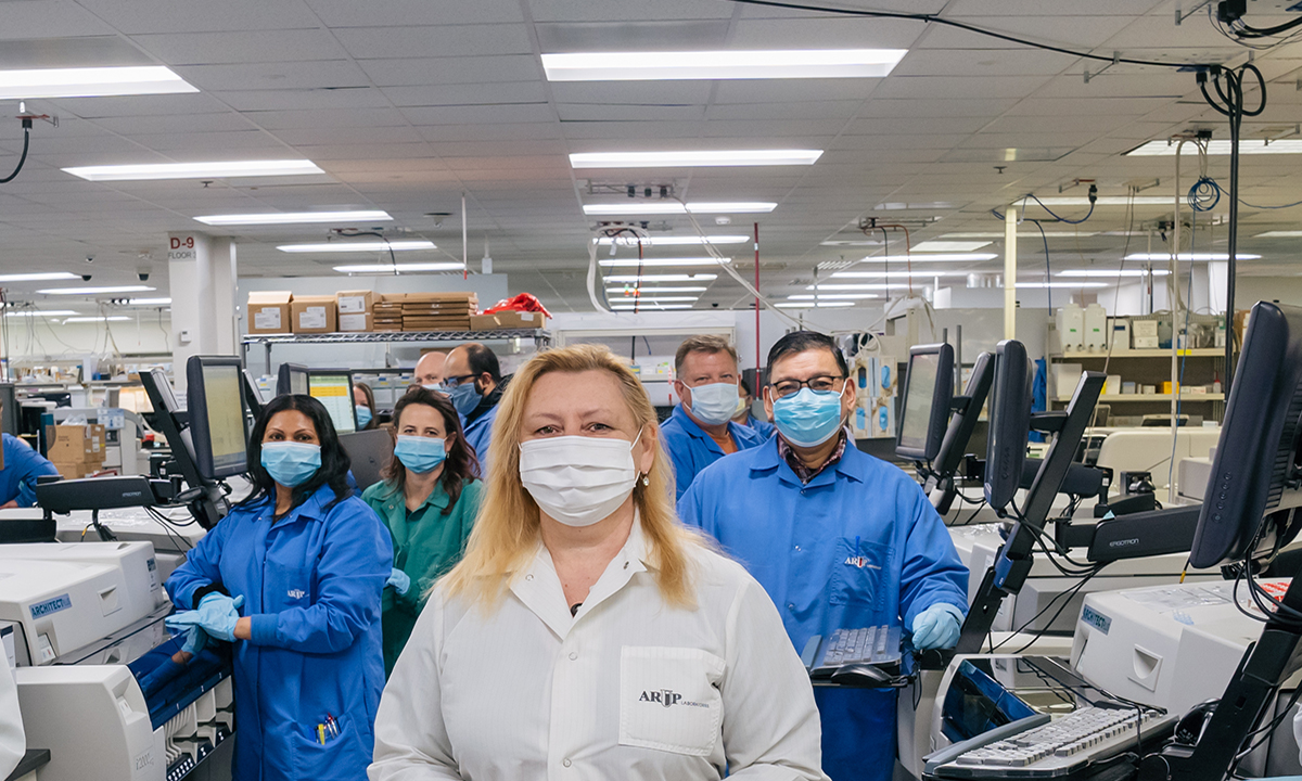 Patricia Slev stands before a group, all in masks, in the lab