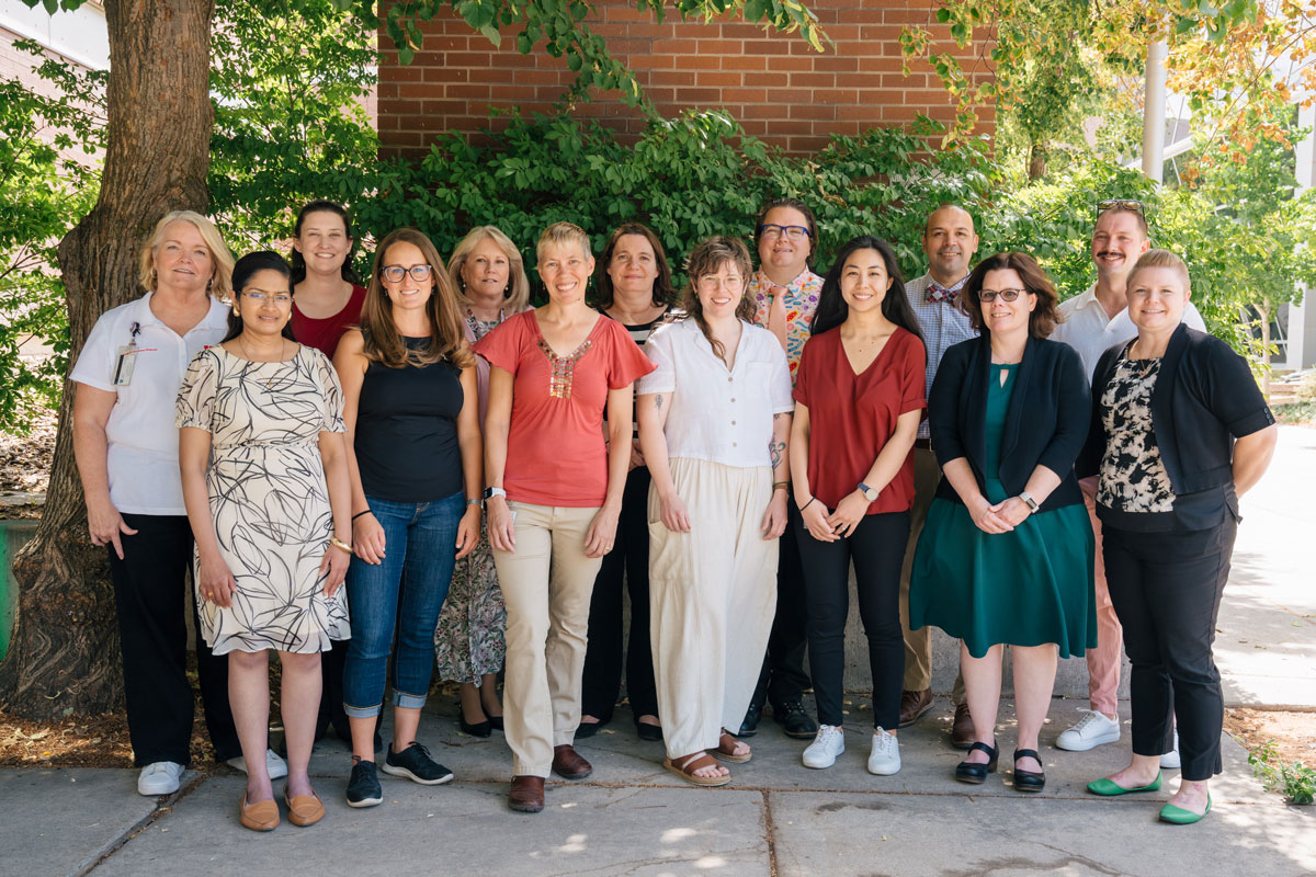 Four women cutting a red ribbon in front of an entrace