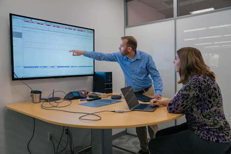 Two people in a conference room looking at a computer screen