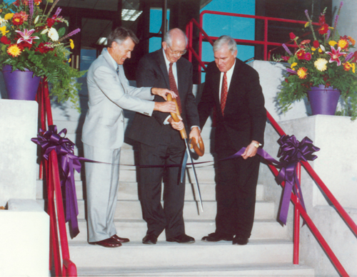 Three men cit a large purple ribbon