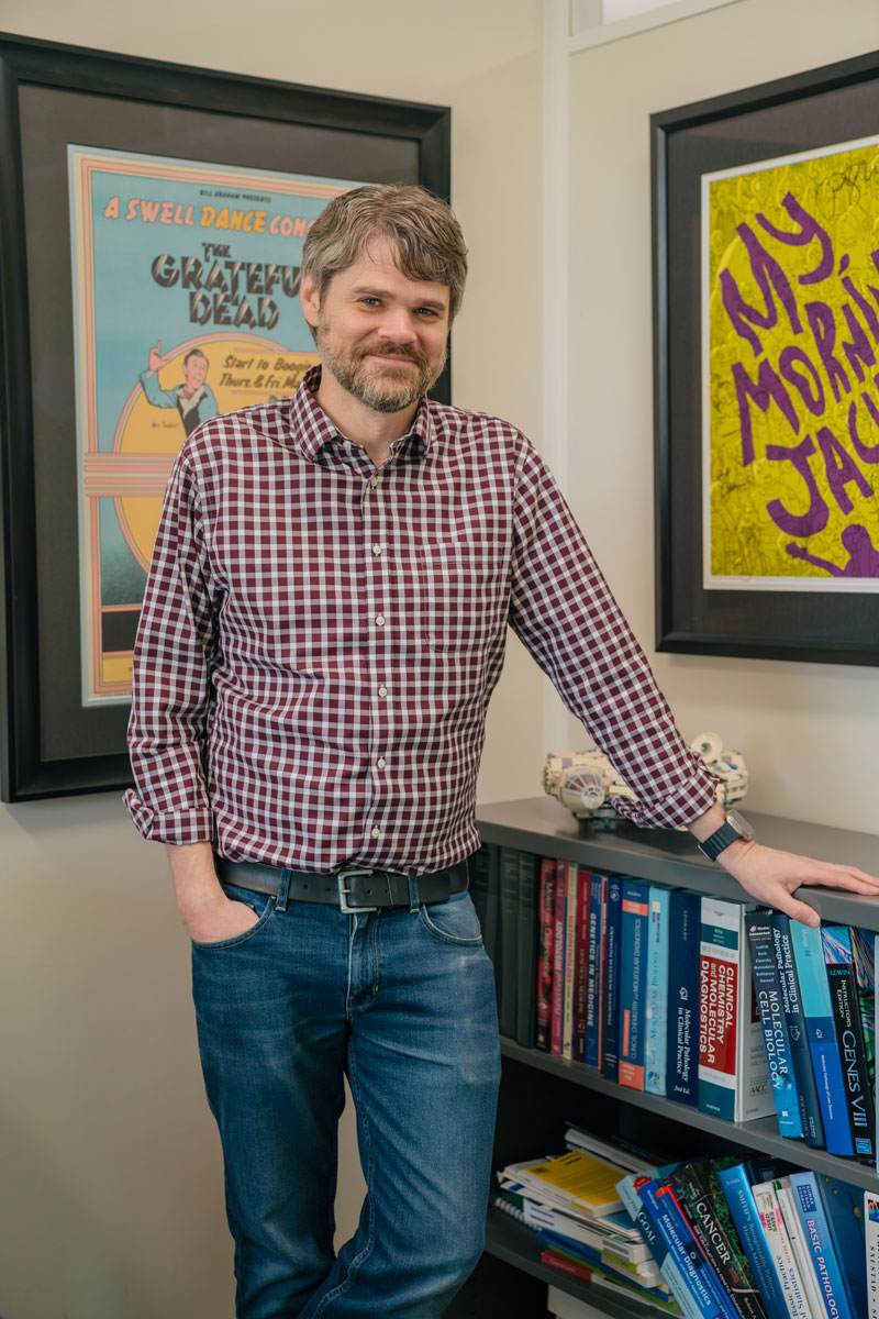 Hunter Best stands in front of a bookshelf