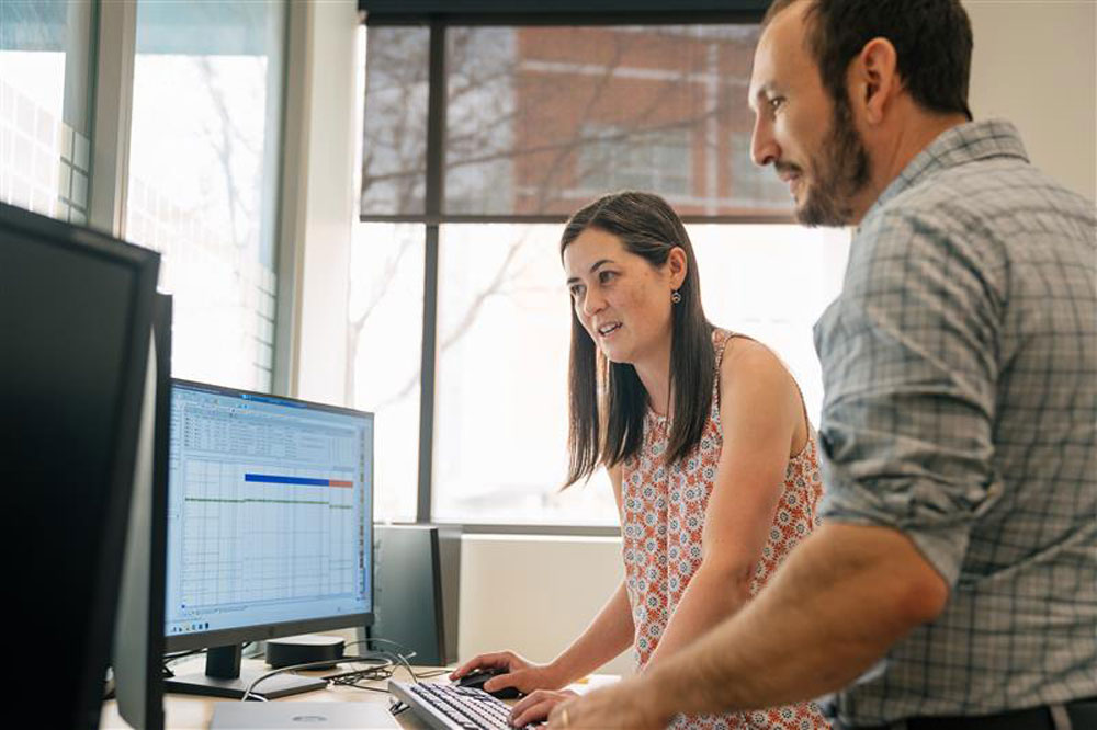 Kelsey Cone in fron of a desk with a computer with with Daniel Reich
