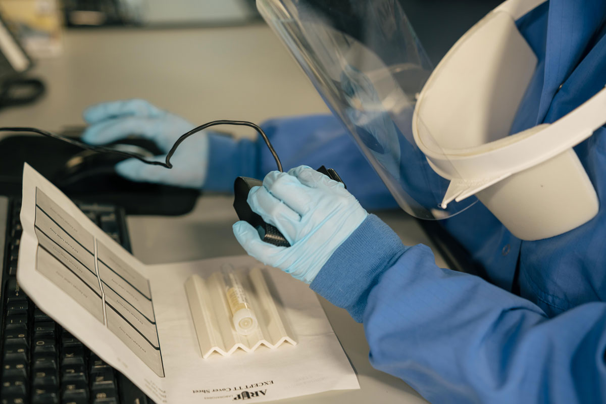 A hand wearing gloves scans specimens