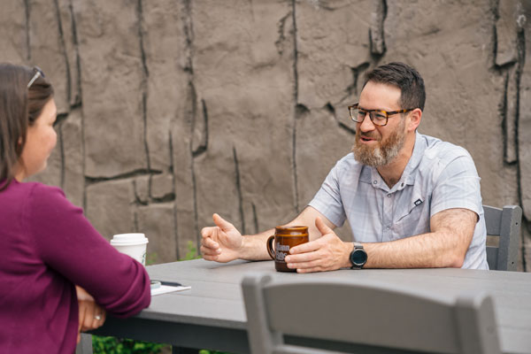 Steven Friedman at a table speaking with a woman sitting across from him