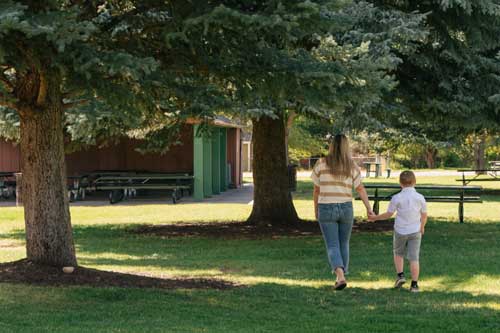 A woman and a child walk in a park